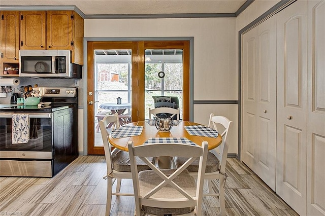 dining space with light wood-style flooring and crown molding