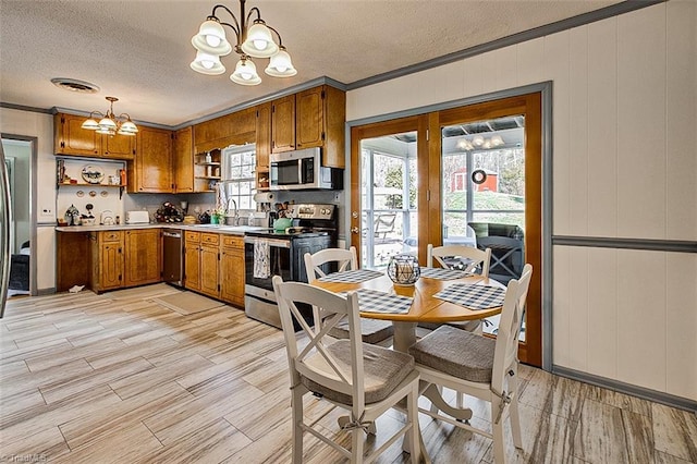 kitchen featuring appliances with stainless steel finishes, a chandelier, brown cabinets, and open shelves