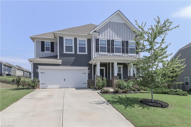 151 Outrigger Ln, Troutman, NC 28166 - view of front of home featuring board and batten siding, concrete driveway, a garage, a front lawn, and covered porch