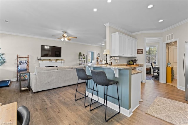 kitchen featuring white cabinets, light wood-style floors, a peninsula, and a breakfast bar