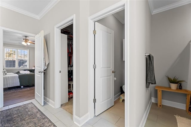 corridor featuring light tile patterned floors, baseboards, and crown molding