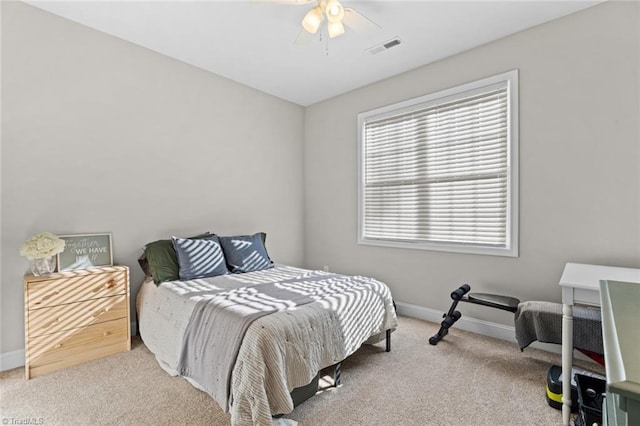 carpeted bedroom featuring a ceiling fan, visible vents, and baseboards