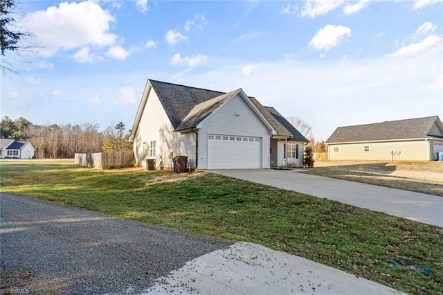 view of front of home with driveway, a front lawn, an attached garage, and fence