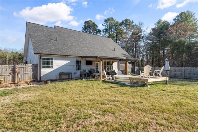 rear view of house with a shingled roof, a lawn, a fenced backyard, and a wooden deck