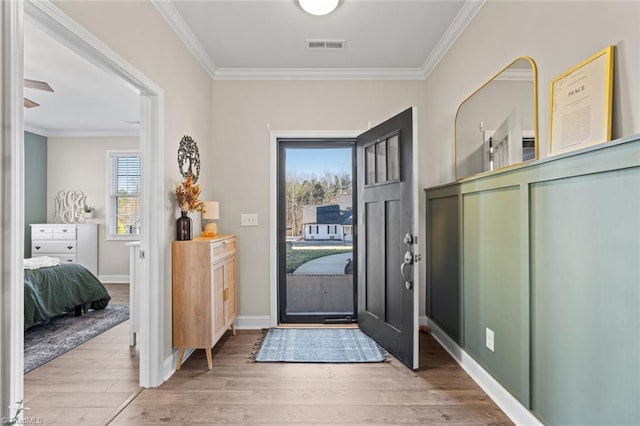 foyer entrance featuring light wood-type flooring, visible vents, crown molding, and baseboards