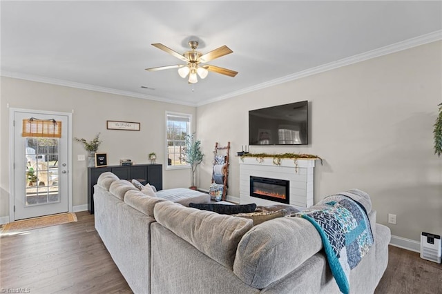 living area featuring dark wood-type flooring, a glass covered fireplace, crown molding, and baseboards