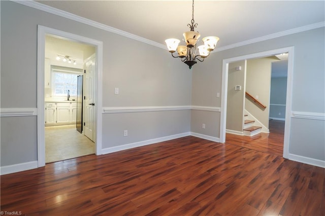 spare room featuring dark wood-type flooring, a chandelier, and crown molding