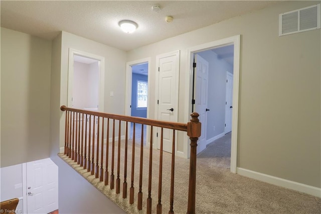 hall featuring a textured ceiling and carpet floors