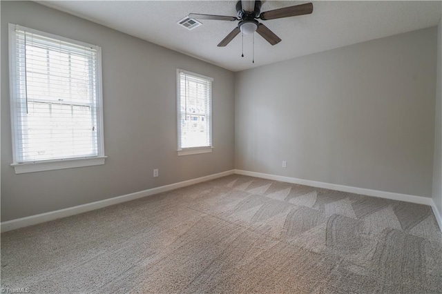 carpeted empty room featuring plenty of natural light and ceiling fan