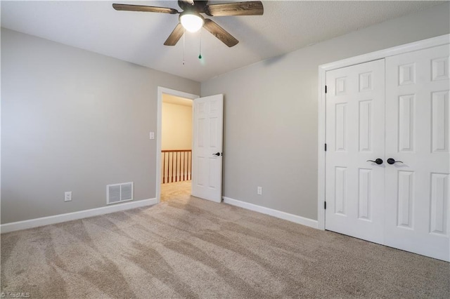 unfurnished bedroom with a closet, light colored carpet, and ceiling fan