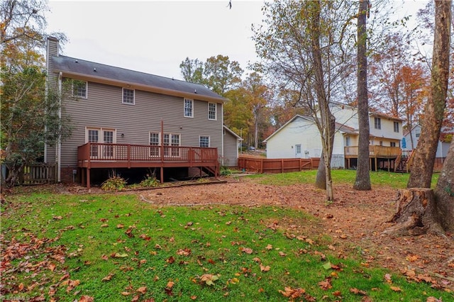 rear view of house with a lawn and a wooden deck