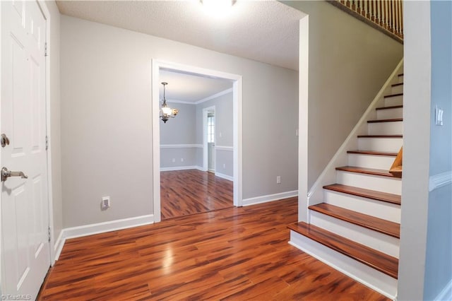 stairway featuring a chandelier, hardwood / wood-style floors, ornamental molding, and a textured ceiling