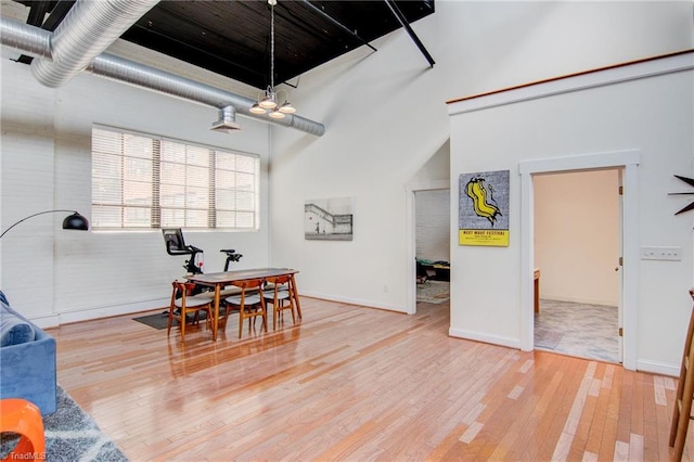 dining area featuring a towering ceiling and hardwood / wood-style flooring