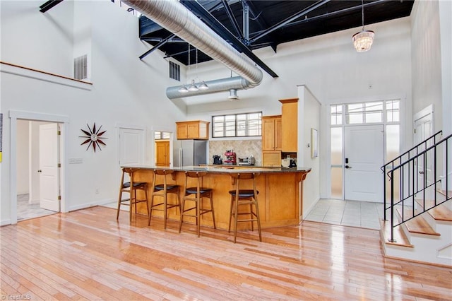 kitchen featuring stainless steel refrigerator, a towering ceiling, and kitchen peninsula