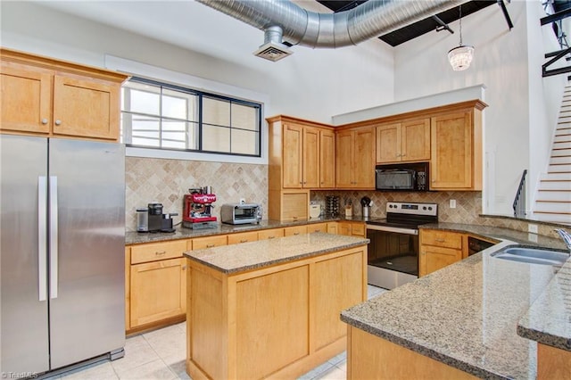 kitchen with light stone counters, sink, a kitchen island, backsplash, and stainless steel appliances