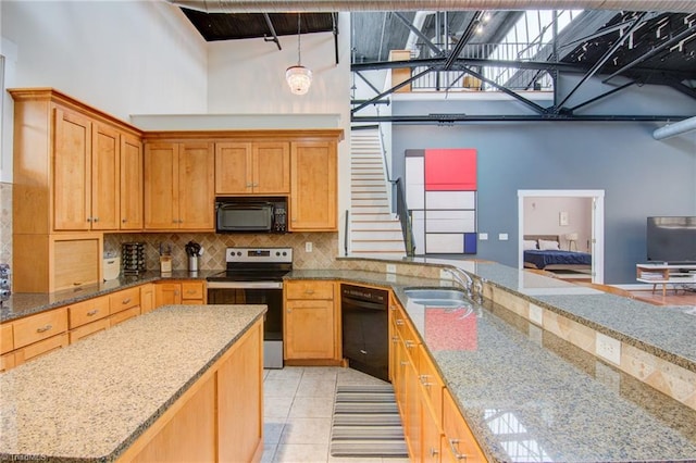 kitchen featuring black appliances, light stone counters, light tile patterned floors, and sink