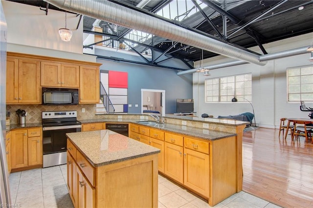 kitchen with black appliances, kitchen peninsula, a center island, and plenty of natural light