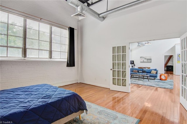 bedroom featuring ceiling fan, brick wall, and hardwood / wood-style floors