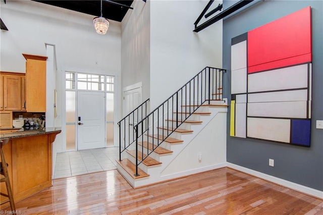 entryway with light wood-type flooring, a towering ceiling, and a chandelier