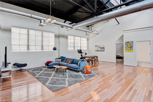 living room with brick wall, a high ceiling, and hardwood / wood-style flooring