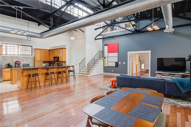 dining space featuring light wood-type flooring and a high ceiling