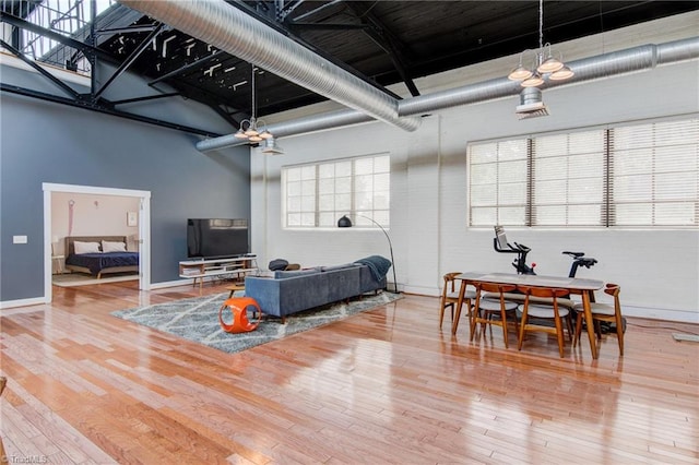 living room with a high ceiling, ceiling fan, and hardwood / wood-style flooring