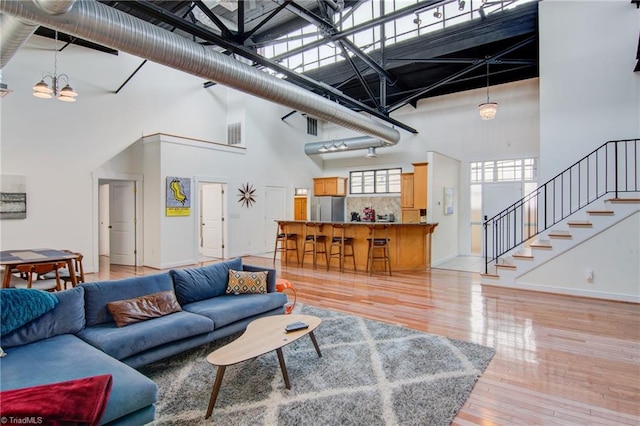 living room with light hardwood / wood-style flooring, a chandelier, and a high ceiling