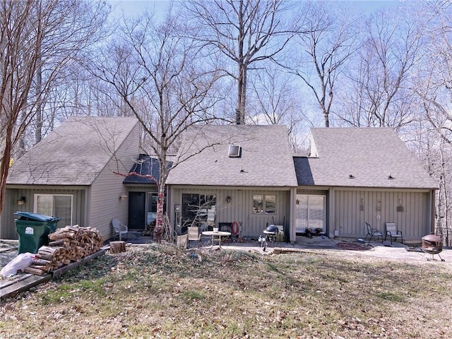 view of front facade with board and batten siding, an outdoor fire pit, a patio, and roof with shingles