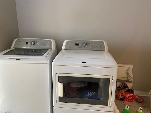 clothes washing area featuring baseboards, washing machine and dryer, and laundry area