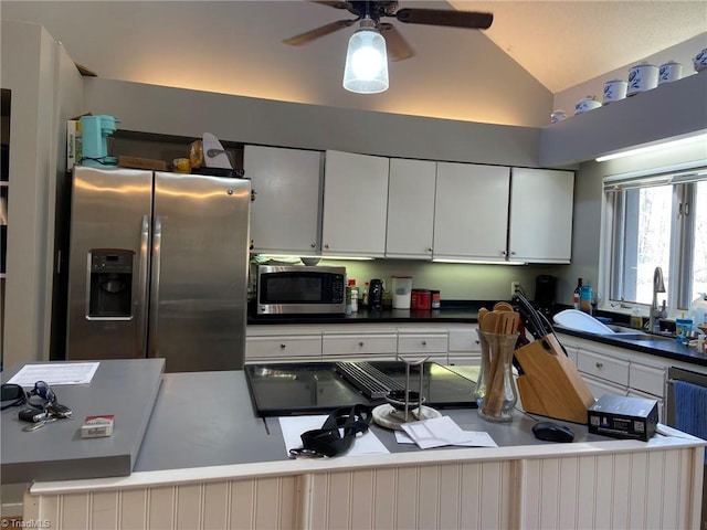 kitchen featuring lofted ceiling, white cabinets, stainless steel appliances, a ceiling fan, and a sink