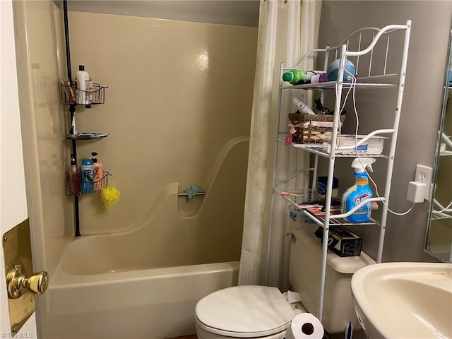 full bath featuring toilet, shower / bath combo with shower curtain, and a sink