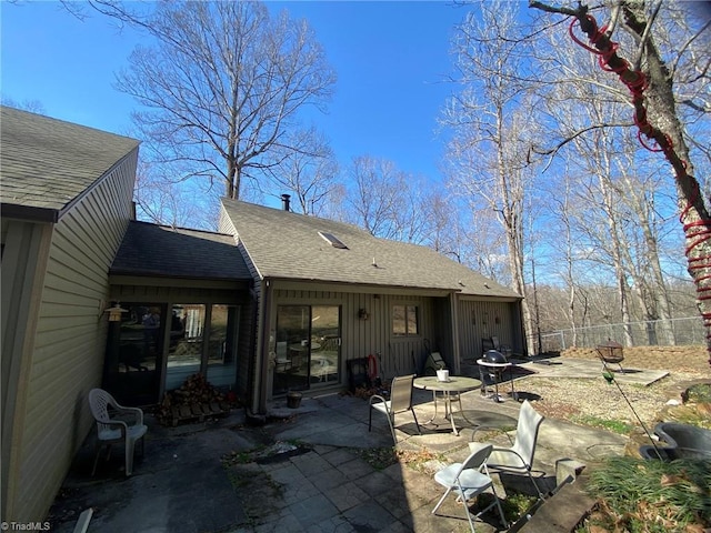 back of property with a shingled roof, a patio, and fence