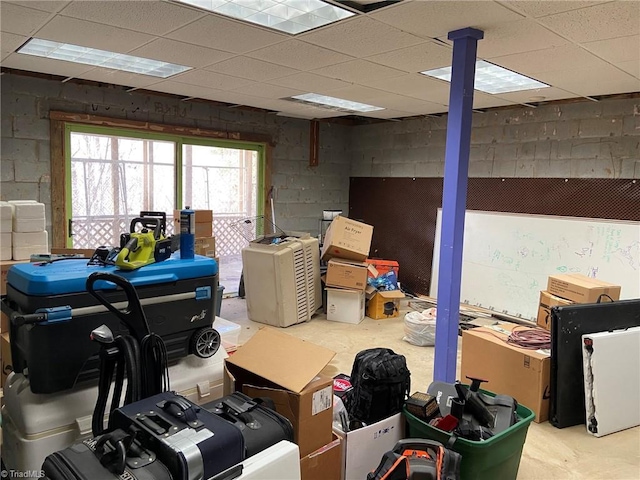 basement featuring concrete block wall and a drop ceiling