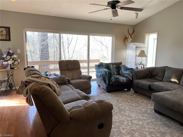 living room featuring wood-type flooring, a textured ceiling, a ceiling fan, and vaulted ceiling