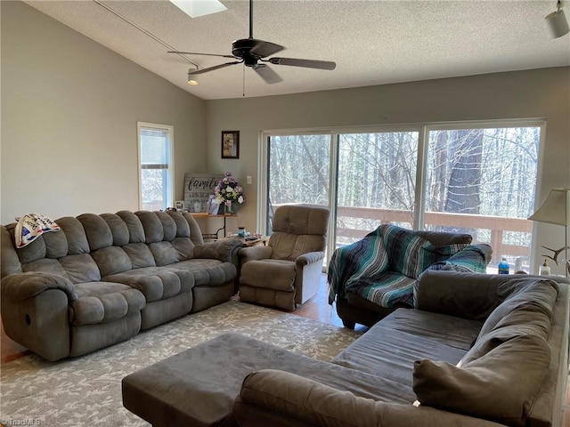 living area with a healthy amount of sunlight, a textured ceiling, a ceiling fan, and vaulted ceiling