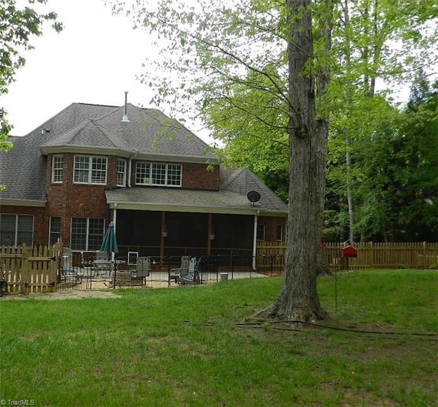 rear view of property featuring a patio, brick siding, and roof with shingles