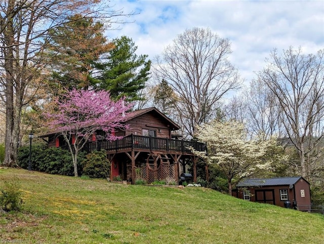 view of front facade with a storage unit, a wooden deck, and a front yard