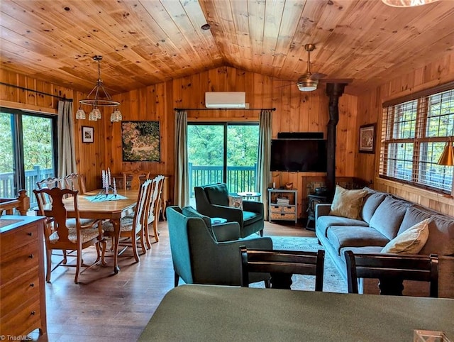 living room featuring wooden walls, wood-type flooring, vaulted ceiling, and plenty of natural light