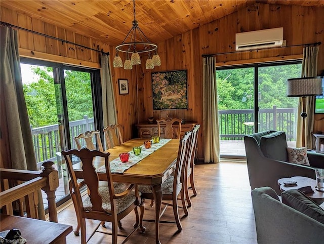 dining space featuring a healthy amount of sunlight, an inviting chandelier, light hardwood / wood-style flooring, and a wall unit AC