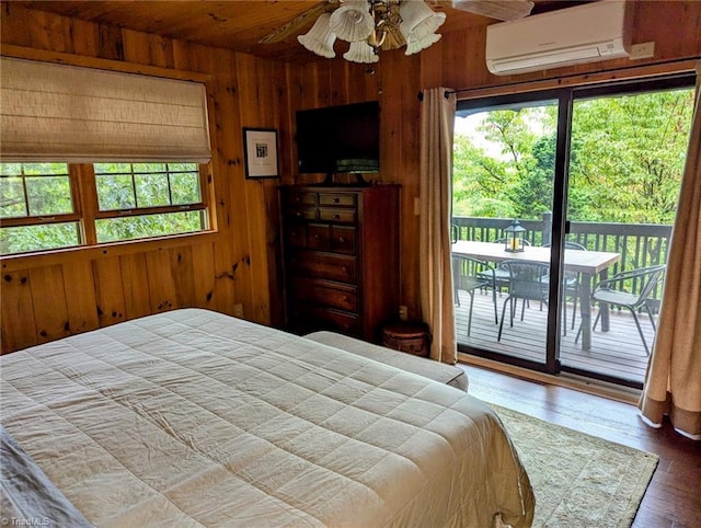 bedroom featuring wood walls, a wall unit AC, access to exterior, and hardwood / wood-style floors