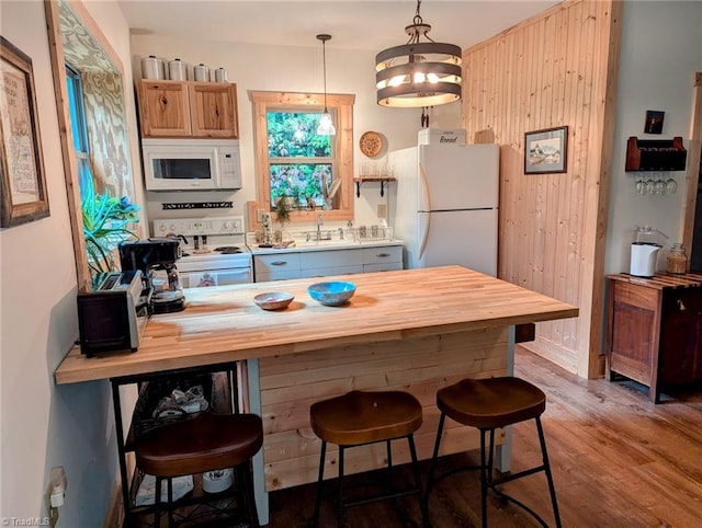 kitchen featuring hardwood / wood-style flooring, white appliances, butcher block countertops, decorative light fixtures, and sink