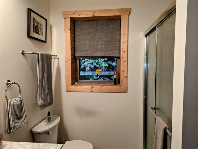 bathroom featuring toilet and a shower with door