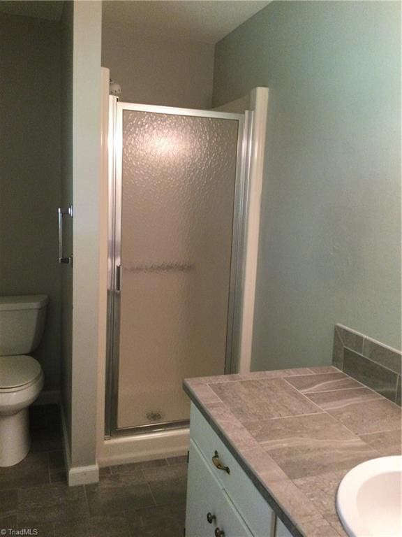 bathroom with an enclosed shower, vanity, and toilet