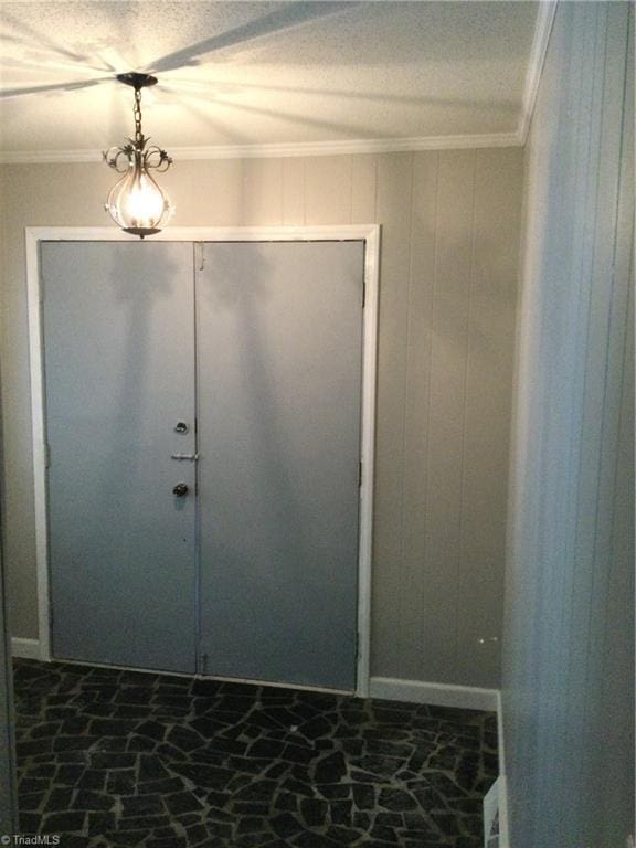 entrance foyer featuring ornamental molding, a textured ceiling, and wood walls