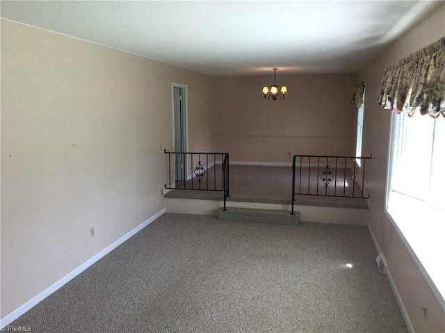 carpeted spare room featuring a notable chandelier