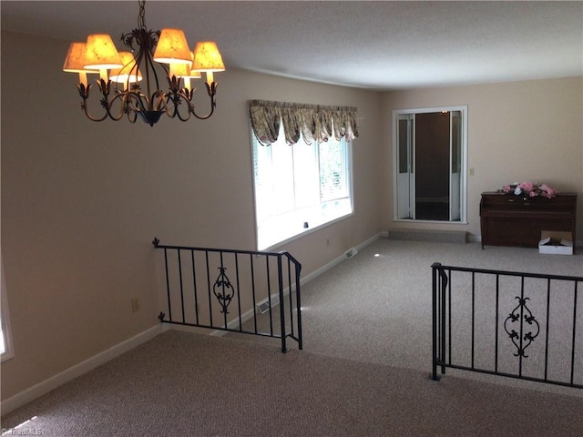 carpeted spare room featuring a notable chandelier