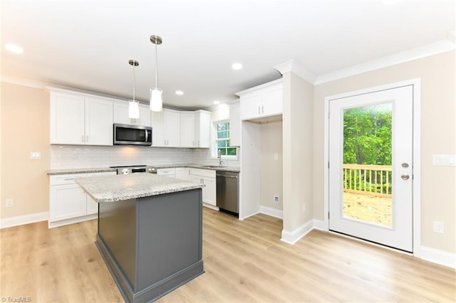 kitchen with stainless steel appliances, white cabinets, light stone counters, and a center island