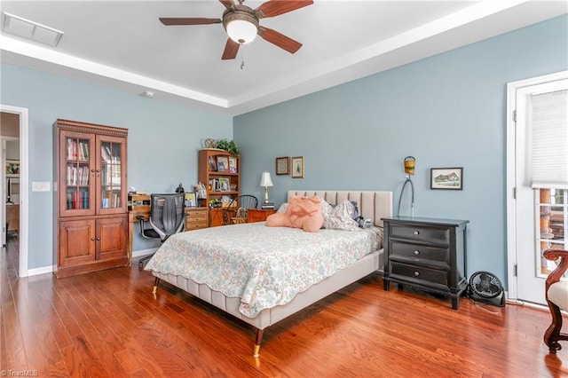 bedroom with a raised ceiling, dark hardwood / wood-style floors, and ceiling fan