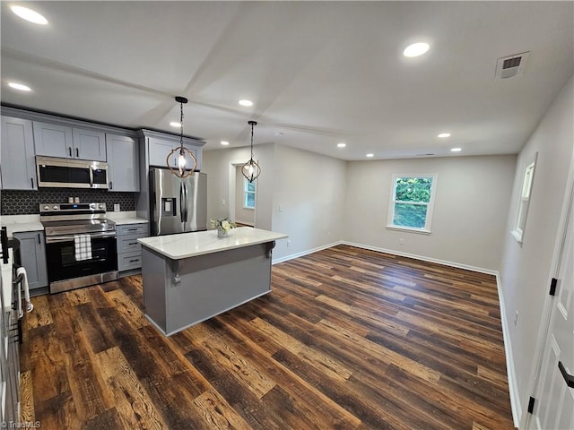 kitchen featuring hanging light fixtures, a kitchen island, gray cabinetry, appliances with stainless steel finishes, and dark hardwood / wood-style floors