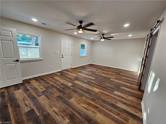 foyer with ceiling fan, dark wood-type flooring, and a barn door